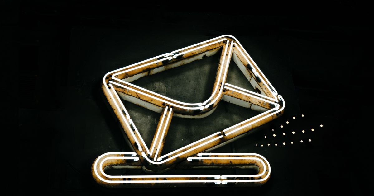 A glowing neon sign in the shape of an envelope against a dark background